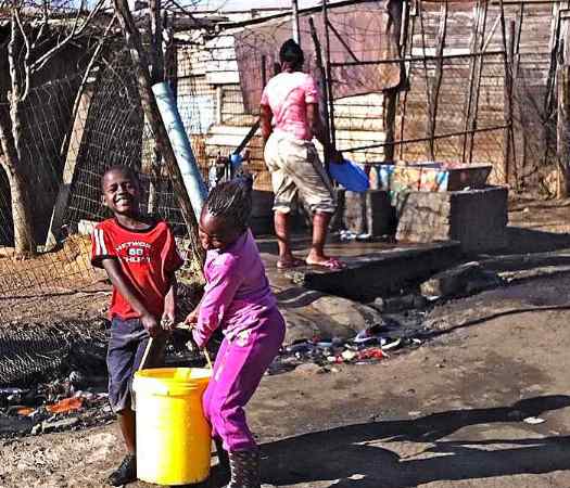 Children carry water from a communal faucet in the Kliptown shantytown adjacent to Soweto. Most dwellings in Kliptown lack water