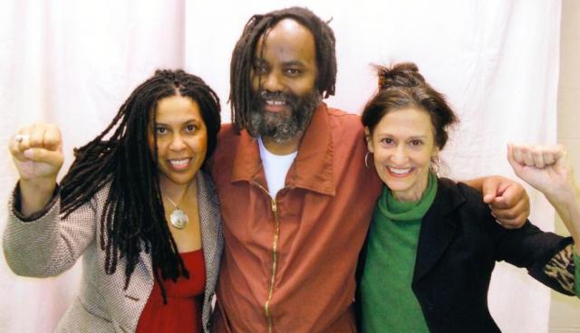 Mumia greets visitors Johanna Fernandez and Heidi Boghosian with a hug